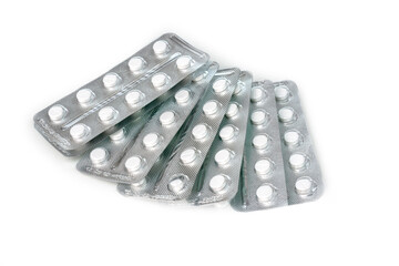 White round tablets in a blister lie scattered on a white background