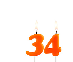 Lit birthday candle - Candle number 34 on white background.