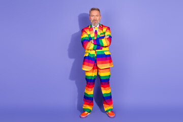 Charismatic older man in rainbow striped suit, standing confidently against a purple backdrop embodying fashion, pride, and individuality