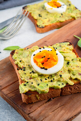 Healthy avocado toasts with eggs on table