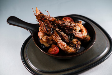 grilled jumbo shrimp casserole or guvec with domatoes, butter garlic sauce and mushrooms served on earth color brown contemporary plates