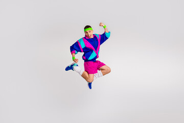Young energetic man jumping in colorful retro sportswear against white background