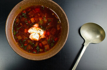 Traditional Ukrainian Beetroot Soup with Various Vegetables, Vegeterian, Tablespoon, on a black table, top view