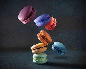 Levitating colored macaroons with various flavors on a dark background