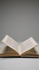 Obraz premium Open book with floating pages against a softly lit gray backdrop