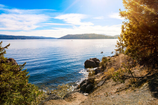 Two kayakers near the rocky shoreline of Tubbs Hill park and hiking trail on the lake in the downtown district of Coeur d'Alene, Idaho.