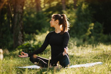 Pretty woman practicing yoga outside in a park at sunny day