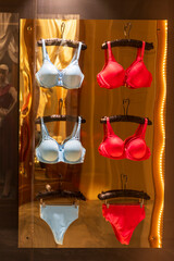 Blue and red bras and panties on hangers in a store window. Window display decoration.