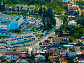 Aerial view of a town with colorful houses, a large blue building, and parked vehicles.