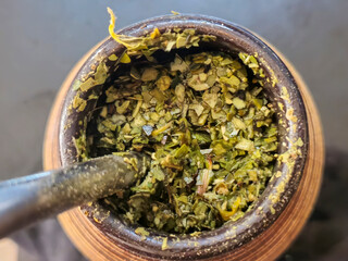 Close-up of dried herbs in a wooden container, showcasing their rich texture and vibrant green color. Perfect for culinary or artistic use.