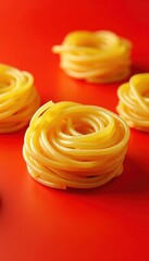 A vibrant display of uncooked spaghetti nests on a bold red background, perfect for culinary-themed projects and food-related marketing.