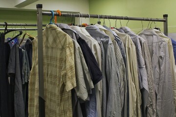 A neatly organized clothing rack with a variety of men's shirts are hanging neatly on hangers, ready to be selected and tried on. Concept of shopping, fashion, retail, and second-hand