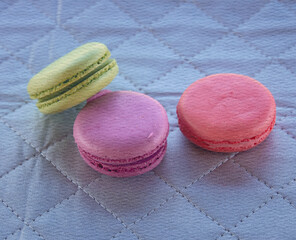 Three macarons of different colors are sitting on a blue background