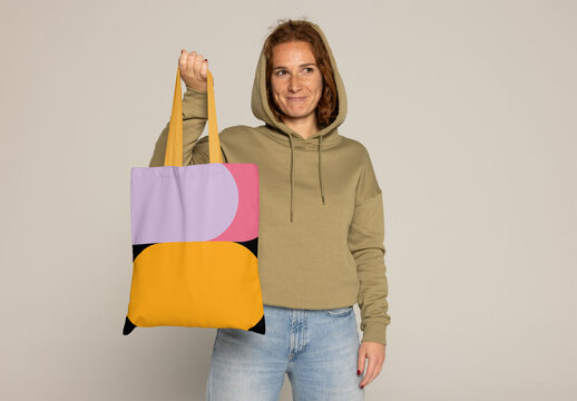 Customizable Tote Bag Displayed by a Woman With Red Hair. PSD mockup. Insert your design, your logo and change color from totebag