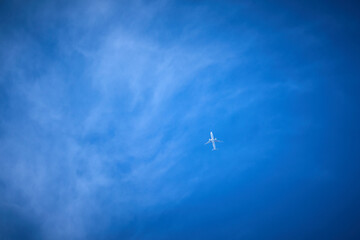 blue sky with wispy clouds and jet