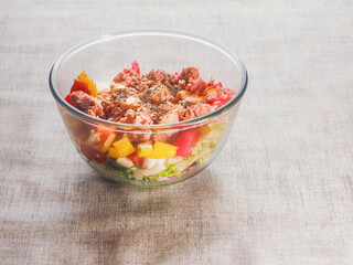 Fresh salad with tuna, peppers, tomato in glass bowl on a simple table cloth. Home made food made from fine high quality ingredients. Weight loss meal.
