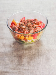 Close up of fresh salad with tuna, peppers, tomato in glass bowl on a simple table cloth. Home made food made from fine high quality ingredients. Weight loss meal.