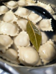 Boiled dumplings are mixed with a large spoon in boiling water. cooking dumplings in a saucepan