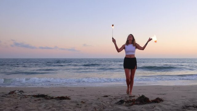 Attractive woman fire dancer spinning flames at the beach. Slow Motion.