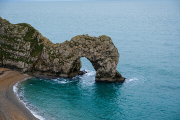 Fototapeta premium Durdle Door limestone arch on the Jurassic Coast in Dorset. Natural landmark. England. Pure clean clear water. Winter cold day at Durdle Door in Dorset, England, UK