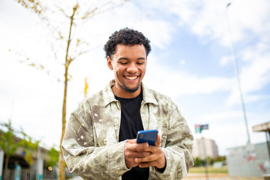Happy young man browsing smartphone in outdoor setting