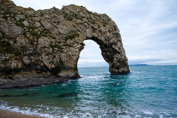 Naklejka premium Durdle Door limestone arch on the Jurassic Coast in Dorset. Natural landmark. England. Pure clean clear water. Winter cold day at Durdle Door in Dorset, England, UK