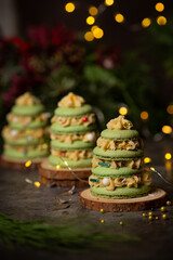 French macaron in the shape of green christmas tree with lights on dark background 