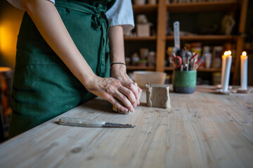 Unrecognizable woman potter hands working clay for ceramics in workshop. Kneading, shaping and preparing raw material for crafting crockery. Small business, artisanal technique, tactile artistry