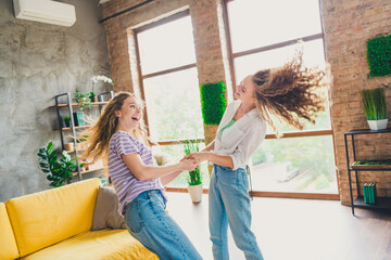 Joyful moment of two young girls dancing in a sunny living room, conveying friendship and happiness.