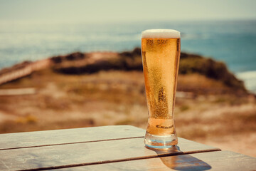 Sunny landscape with beer glass at outdoor bar. 