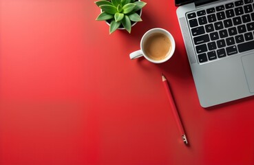 Top view of laptop computer with red pencil, cup of coffee on red desk. Simple, modern workspace setup. Red color scheme creates focus on productivity tools. Flat lay studio shot with copy space for