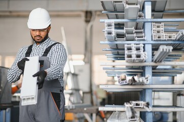 Operator of machine. Industrial worker indoors in factory. Young technician in white hard hat