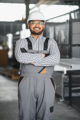 Young Indian male engineer wearing safety workwear standing in the factory