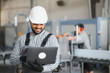 Young Indian male engineer wearing safety workwear standing in the factory