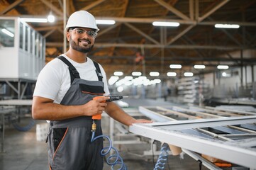 Operator of machine. Industrial worker indoors in factory. Young technician in white hard hat