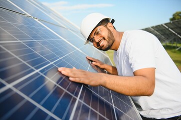 Portrait of Young indian male engineer standing near solar panels, with clear blue sky background, Renewable and clean energy. skill india, copy space