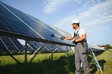 Indian handyman cleaning solar panels form dust and dirt