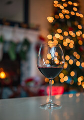 Red wine in front of fireplace and a Christmas tree 