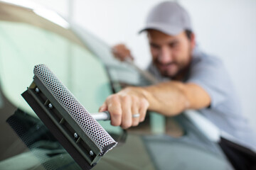 a nmale worker cleaning the car window
