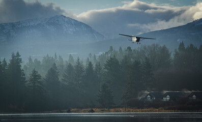 Scenic Light Aircraft Landing Over Misty Forest and Mountain Landscape. Cessna 172 single engine...