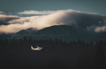 Scenic Light Aircraft Landing Over Misty Cabins and Mountain Landscape. Cessna 172 single engine...