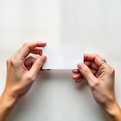Two hands hold blank white business card. Hands, card isolated on plain white surface. Business card mockup for branding marketing purposes. Modern, clean design. Perfect for presentation