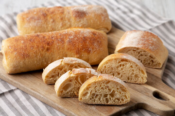Homemade Sliced Ciabatta Bread on a wooden board, side view.