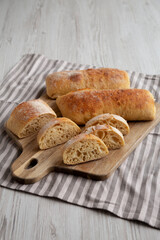 Homemade Sliced Ciabatta Bread on a wooden board, side view.