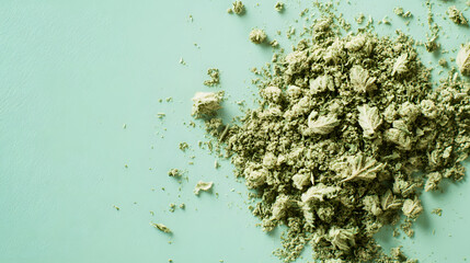 A dreamy arrangement of finely ground cannabis and buds scattered over a pastel-colored surface.