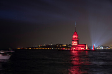 Fototapeta premium Uskudar light show Maiden's Tower during Tukey Republic day celebrations. Ataturk, Turkish flag and Istanbul Municipality sembols on tower with lights.