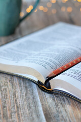 Open holy bible book with pencil and cup of coffee on wooden table. Selective focus. Studying...