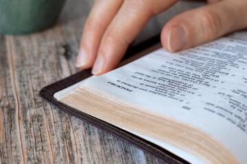 Christian bible study and reading with hand on top of open holy book. Close-up. Selective focus....