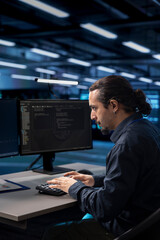 Admin typing on desktop PC in server farm establishment, ensuring data remains shielded from...