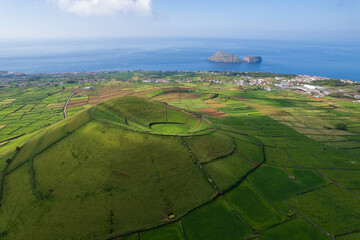 Aerial view of Terceira islans in Azores, Portugal. Volcanic landscape.  Drone shot of ancient Pico Dona Joana volcano and  cabras islet. Green fields in rural environment.